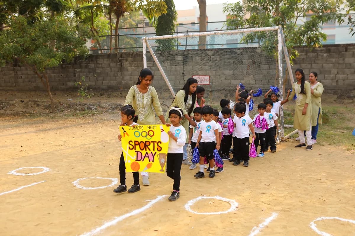 Little ones marching with sports day banner and pom-poms during opening ceremony parade