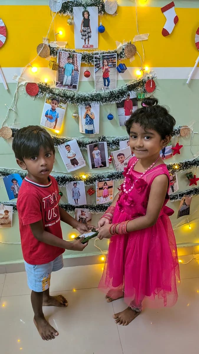 Preschoolers exchanging wrapped gifts beside a decorated Christmas tree