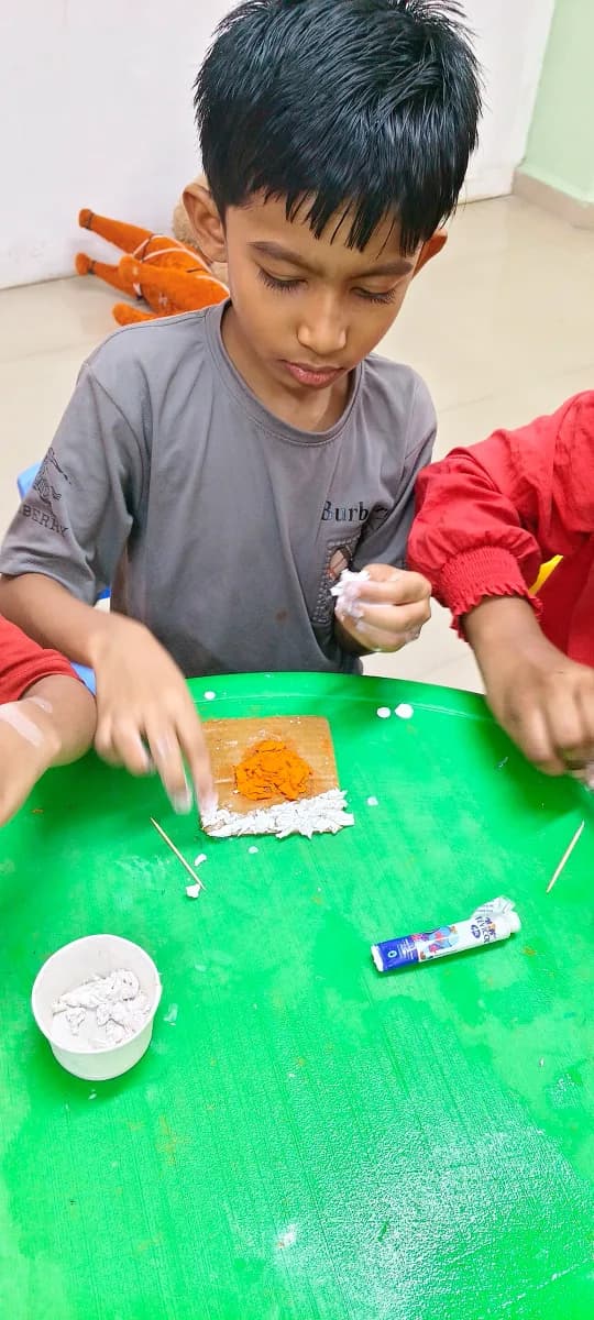 Children sitting at table engaged in creative paper and glue craft making
