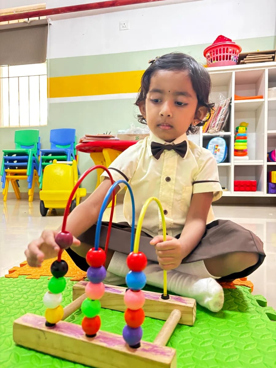 Child working on wooden geometric puzzle tiles at Montessori learning desk