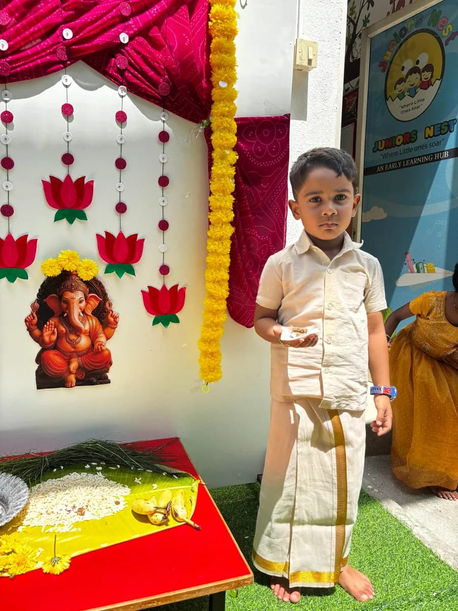 Preschool students seated together offering flowers to clay Ganesha idol