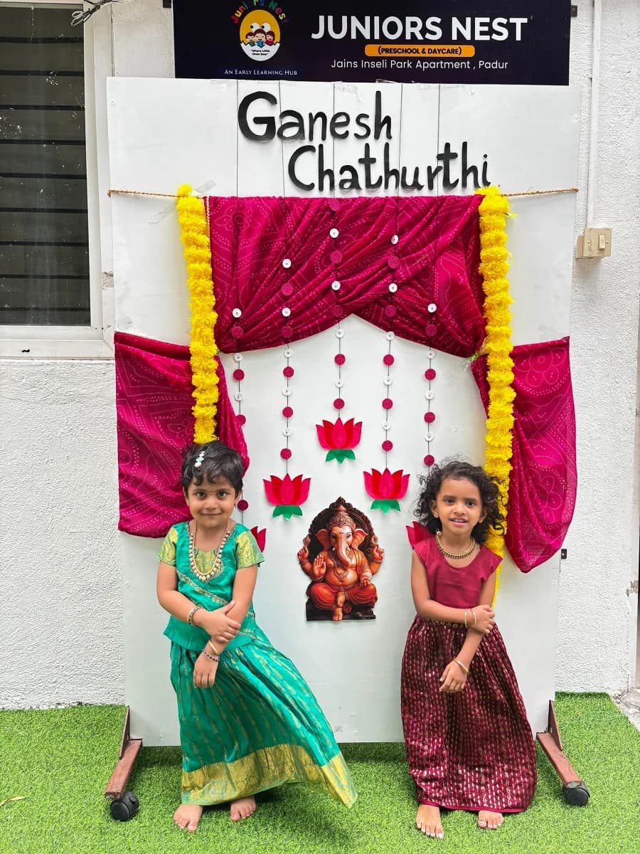 Little girls dressed in traditional silk pavadai celebrating Vinayagar Chaturthi in front of decorated stage